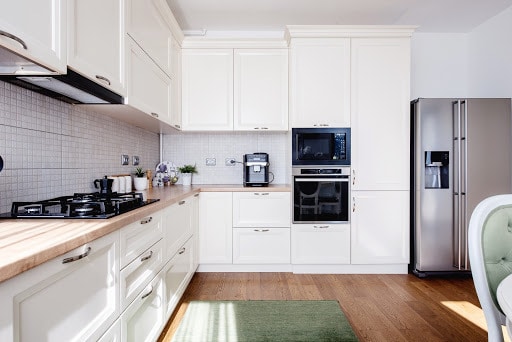 Modern kitchen interior with hardwood floors and wooden white creamy furniture