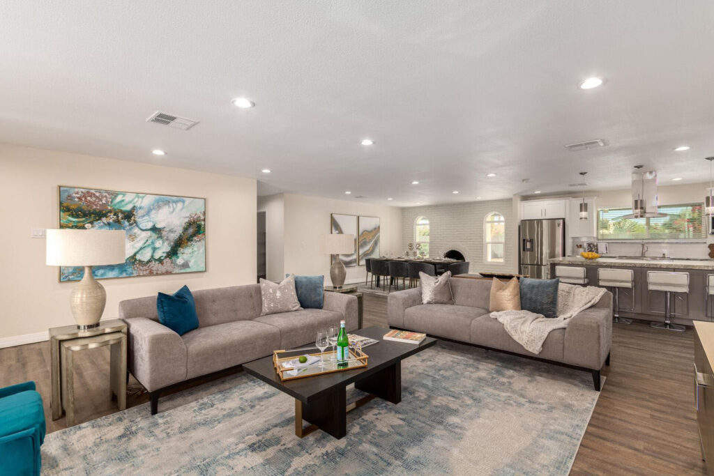 Open-concept living room with two gray sofas, a blue area rug, and a kitchen island in the background