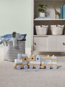Child's bedroom with soft neutral carpet, a storage basket, and wooden toys